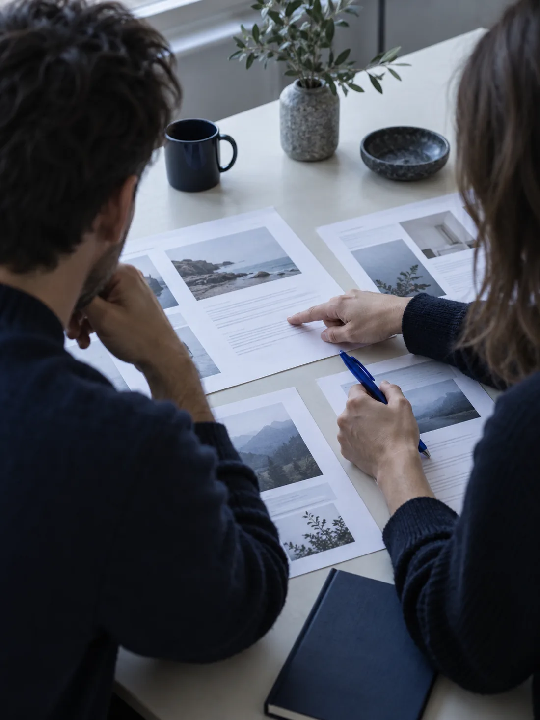 Two people at a table reviewing printed page layouts together